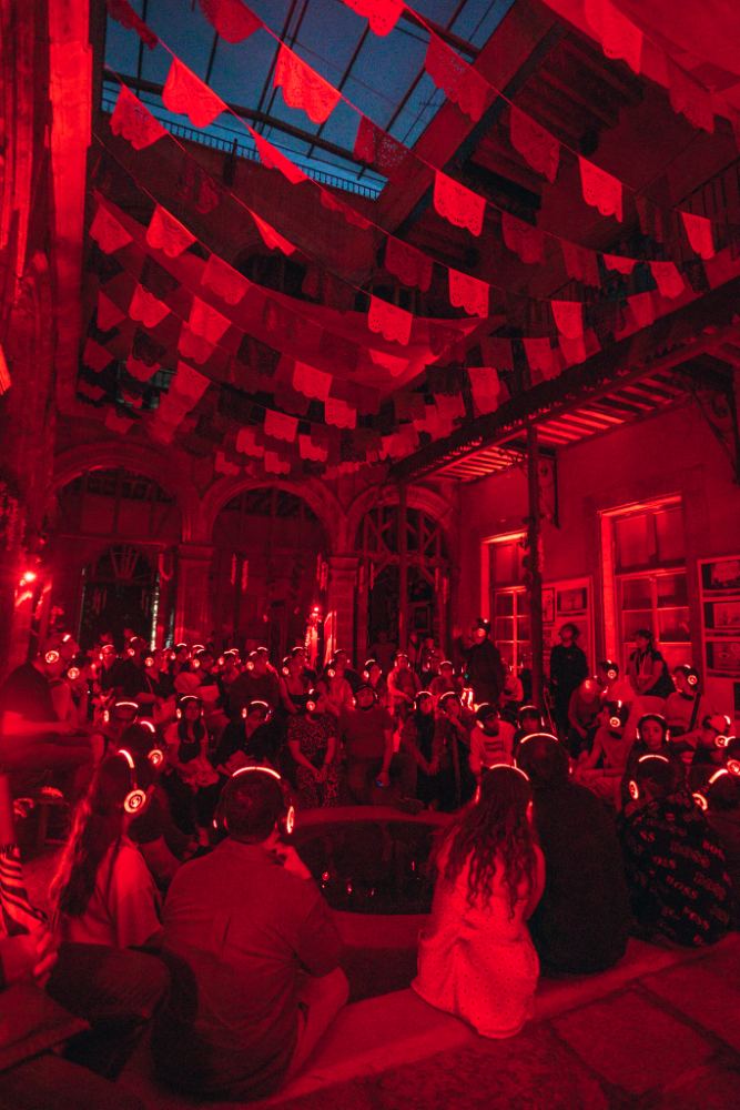 Patio iluminado en rojo con papel picado durante la función