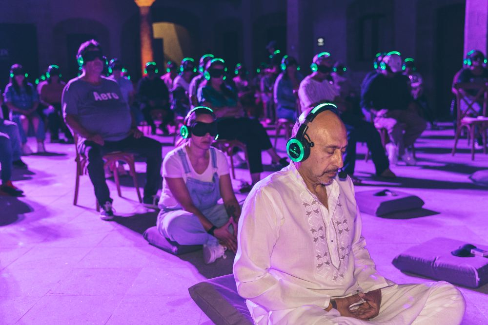 Sesión de meditación grupal con audífonos y antifaces luminosos
